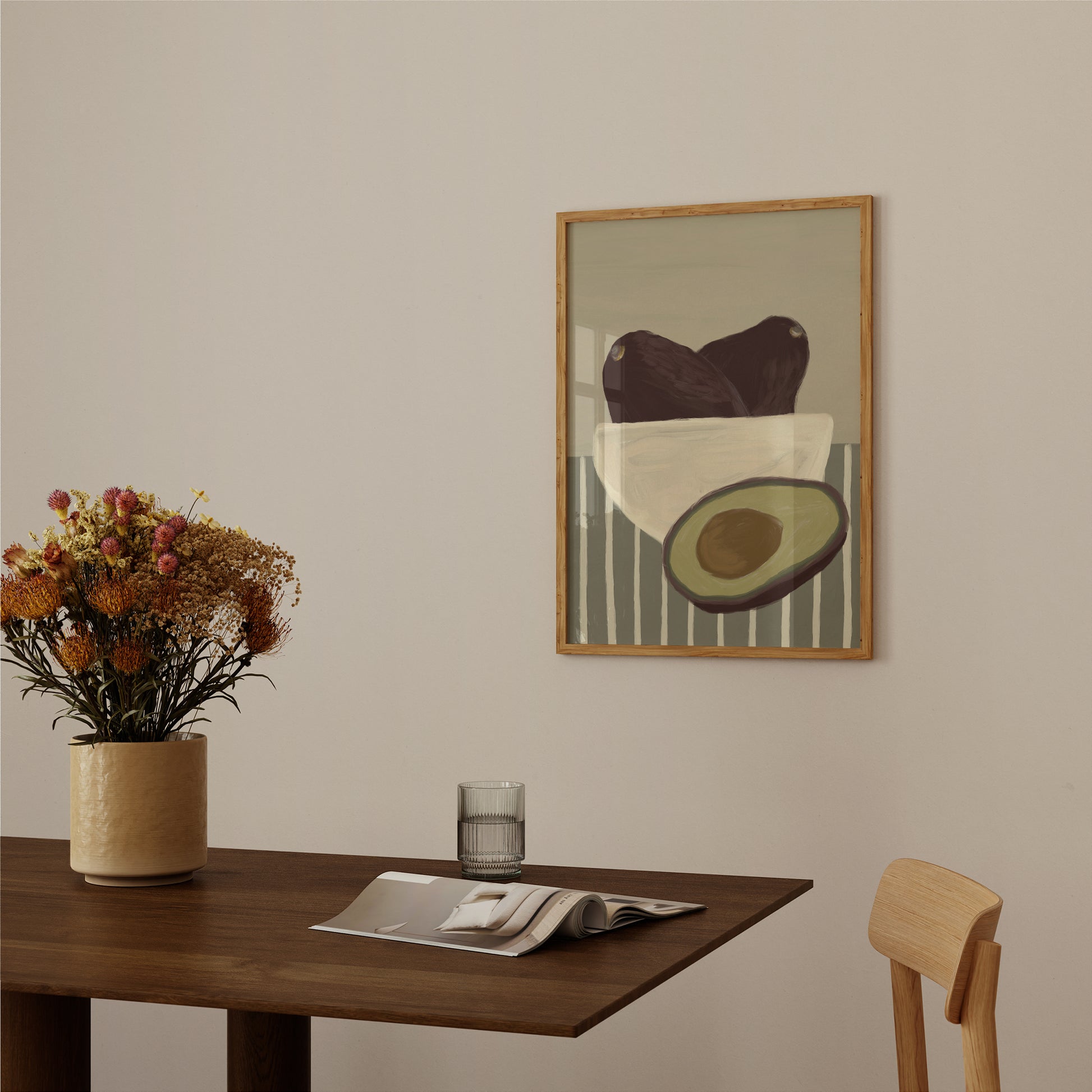 Avocado still life poster in wooden frame above dining table, minimalist food wall art print for kitchen decor.