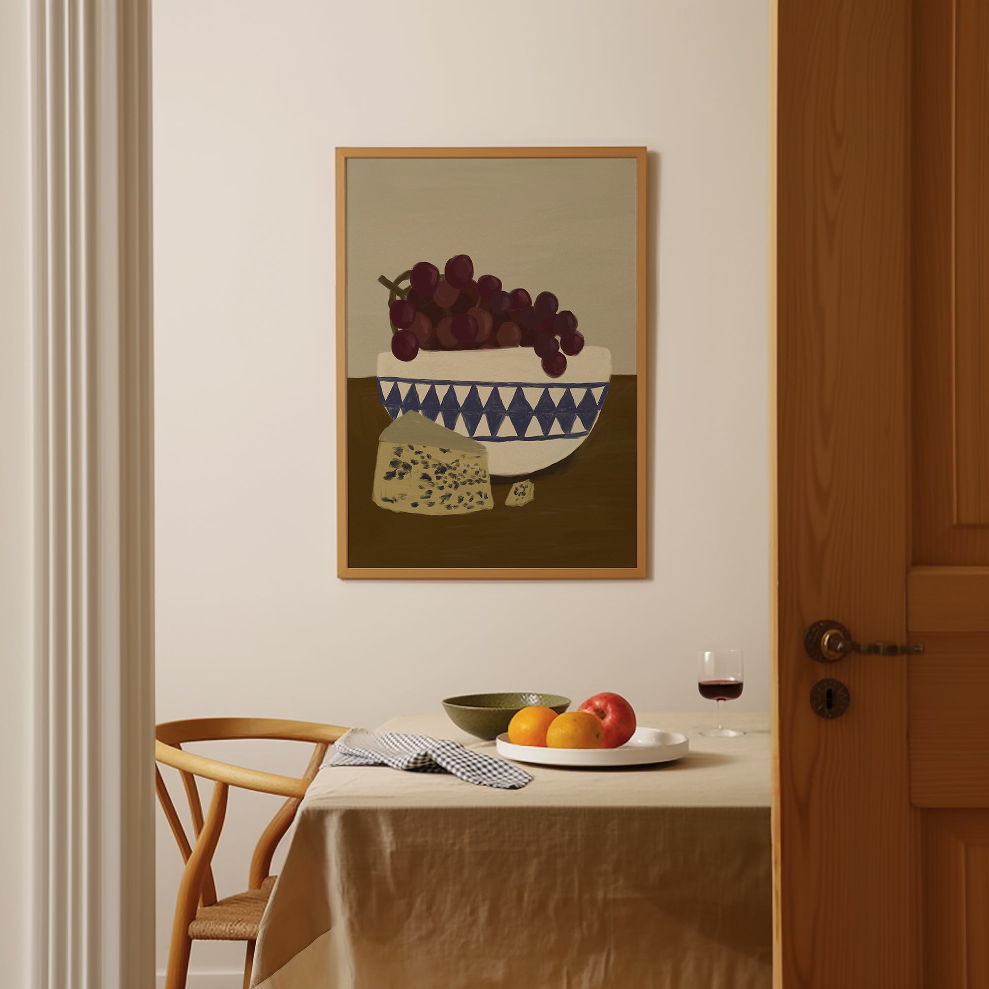 Framed grapes and cheese still life wall art above dining table, modern food poster adding warmth to kitchen décor.