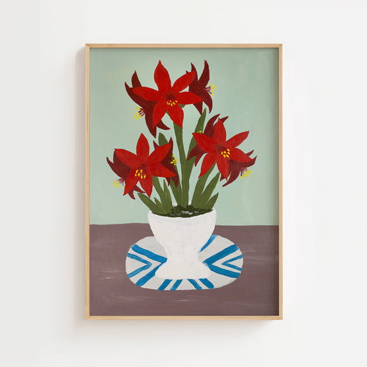 Still-life painting of red amaryllis flowers in a white vase on a blue-and-white plate against a muted green background. Botanical wall art print with mid-century charm.