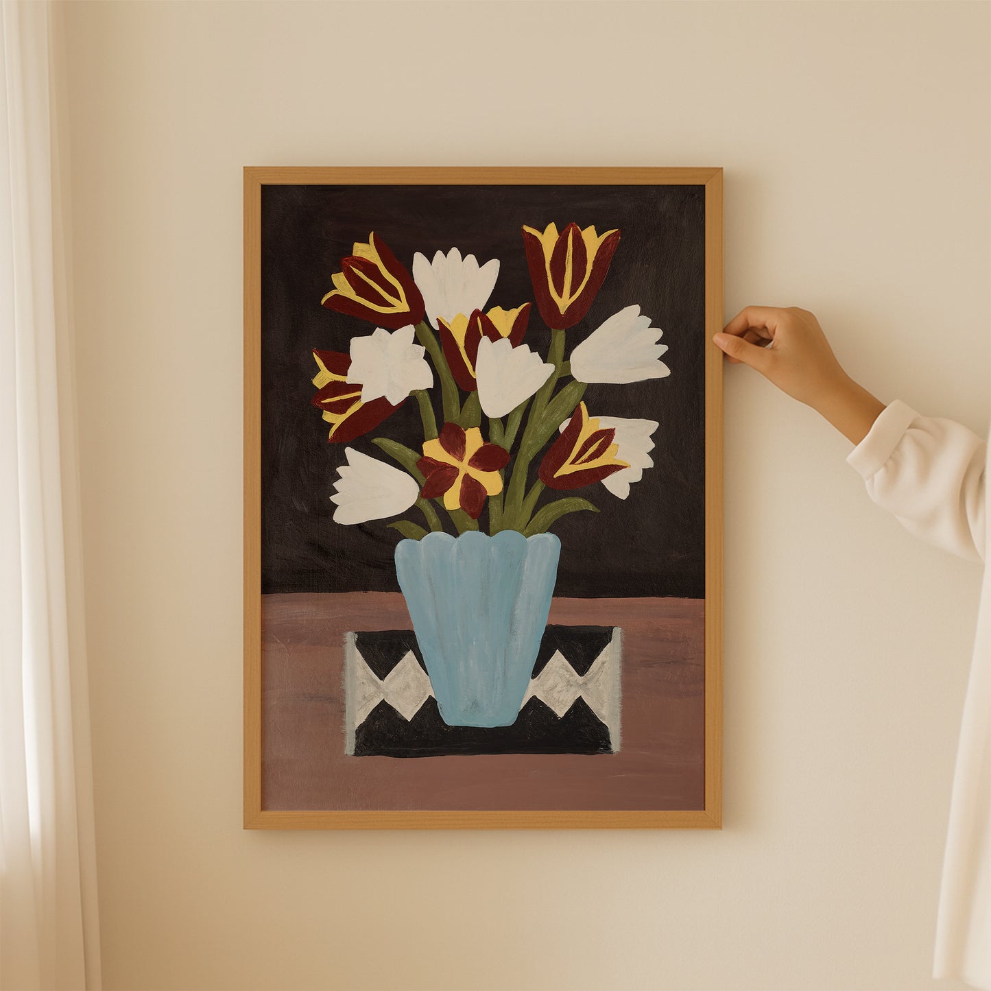 Person hanging tulip bouquet still life art print in a cozy home setting. Botanical wall art with blue vase and warm color palette for modern, minimalist, or bohemian decor.