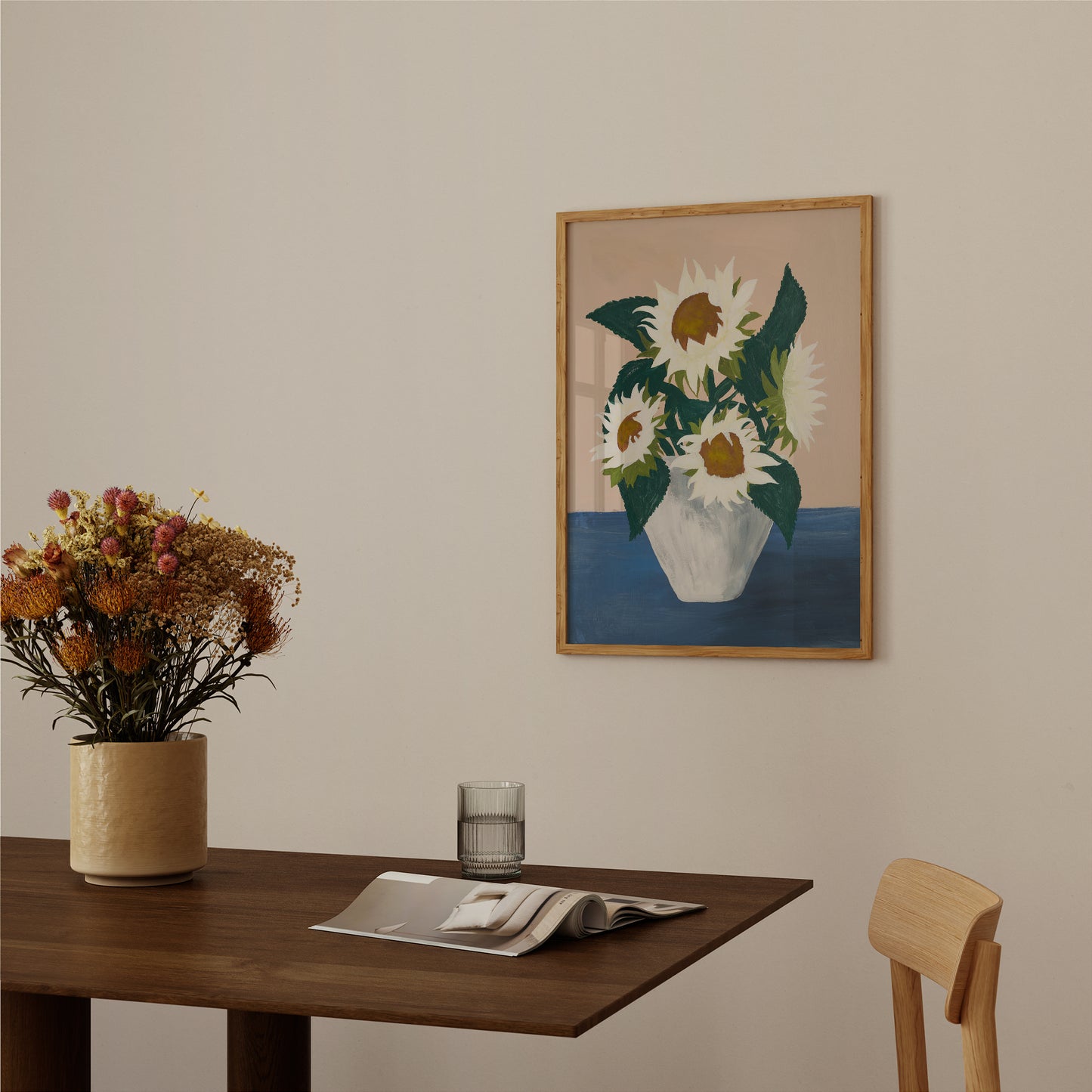 White sunflower wall art framed above a table with vase of flowers. Botanical art print styled in warm neutral room with mid-century influence.
